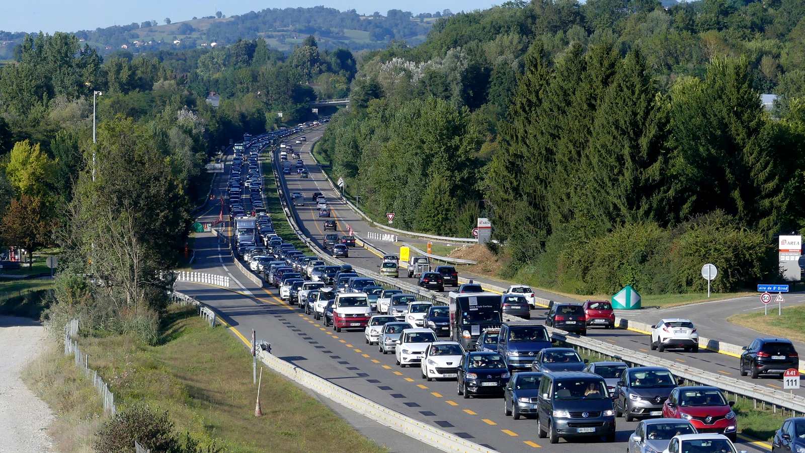 File de voitures sur l'autoroute A41 à Entrelacs, en Savoie, entre des collines boisées, près de l'aire de Saint-Girod