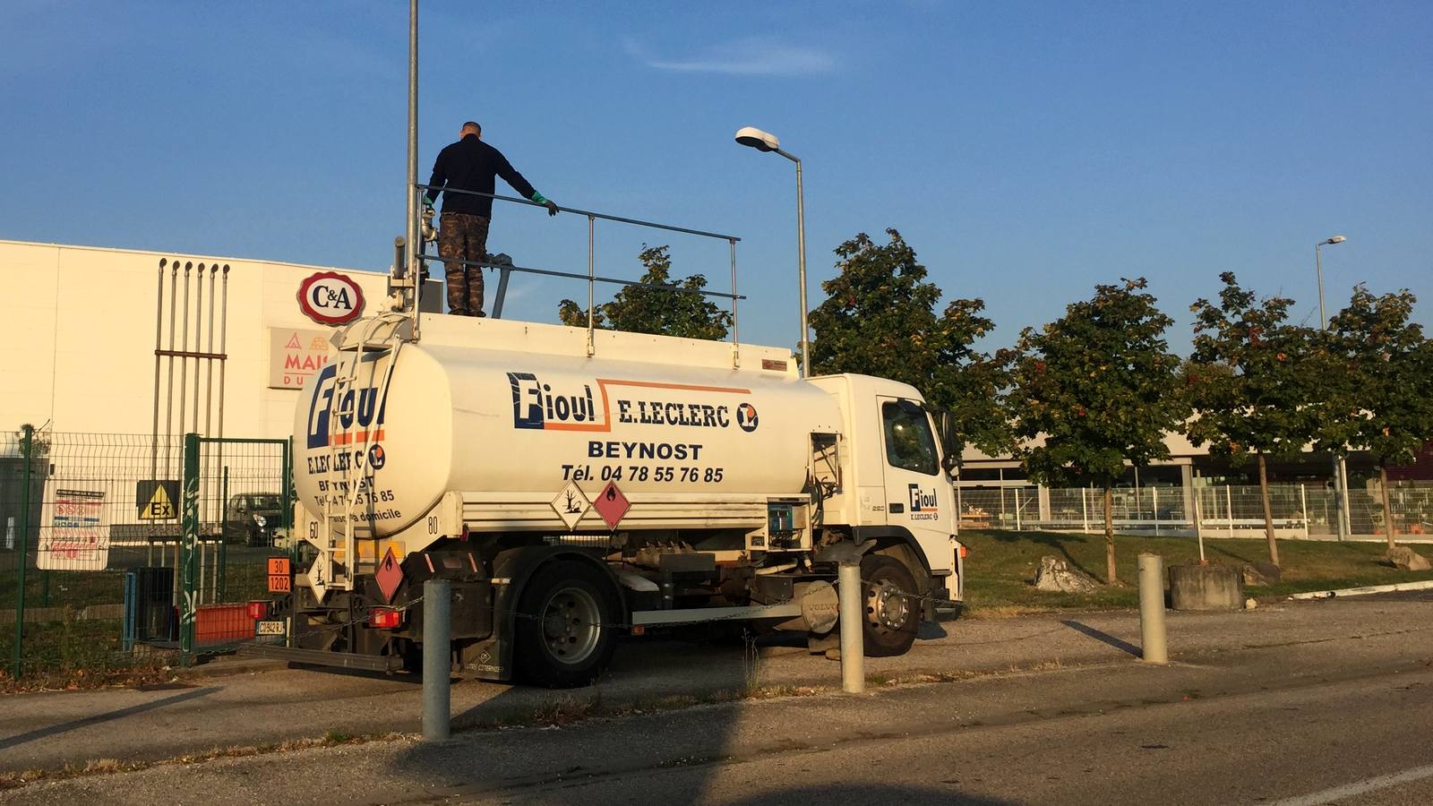 Camion-citerne de livraison de fioul domestique stationné sur un parking de zone commerciale à Beynost, dans l'Ain, un livreur debout sur la citerne